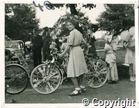 A black and white photograph of a young woman with her decorated bicycle at the Bike Parade, Fairfield, Buxton. Possibly 1942.