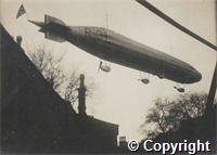 Black and white photograph of airship R34 in the air above roofline